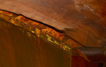 een blad van een antiek meubel waarvan het fineer is losgeraakt